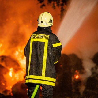 Ein Feuerwehrmann steht vor einem Flammeninferno. (Symbolbild) Die freiligen Feuerwehrleute im Kreis Bad Kreuznach sind im Dauereinsatz. Wegen der Trockenheit gibt es viel mehr Brände als üblich. 