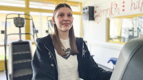 Die 16-jährige Miriam sitzt auf einem Trimmrad im Sportraum der Edelsteinklinik, an dem sie regelmäßig trainiert.