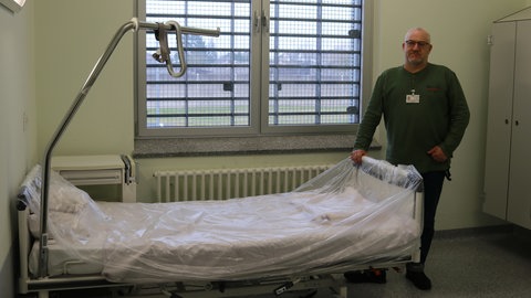 Pflegedienstleiter Marco Strasser neben einem Bett im neueingerichteten Pflegezimmer.