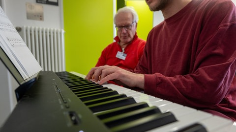 Musiker Bernd Oster (links) bringt Häftling Vladi das Klavierspielen in der JVA Wittlich bei. 