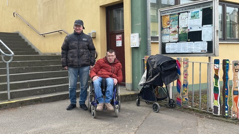 Rolllstuhlfahrer Patrick Loppnow und Michael Scheiwen stehen vor dem Eingang zum Pfarrsaal St. Bonifatius. Dieser dient am kommenden Sonntag als Wahllokal.