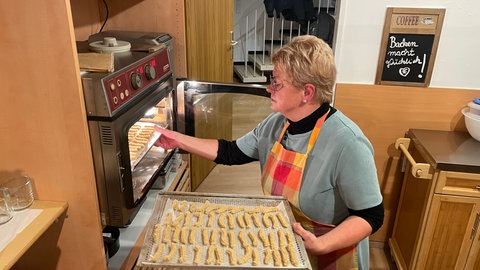 Konditorin Gabi Gores-Kirwald schiebt Spritzgebäck auf einem Blech in den Backofen