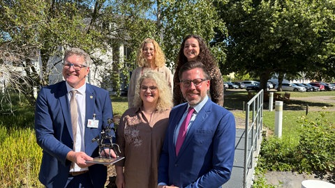 Der Leiter der JVA Wittlich Jörn Patzak hält den Preis der Bundesarbeitsgruppe Suizidprävention in Händen.