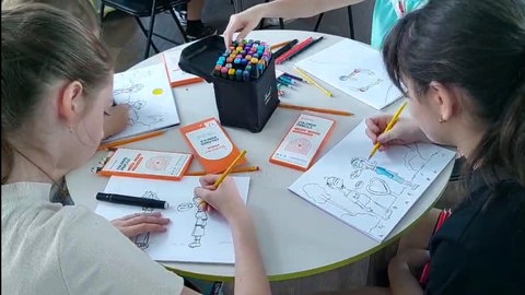 Johannes Kolz mit Kindern und Jugendlichen bei einem Zeichenkurs in einem Klassenzimmer in Isjum. 