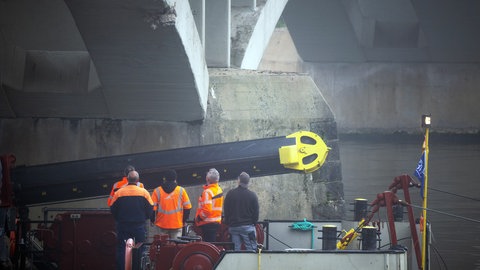 Fachleute untersuchen die Moselbrücke bei Longuich auf Schäden, die ein Frachtschiff nachts verursacht hat. Das Schiff hat bei der Bergabfahrt zwei Brücken gerammt.