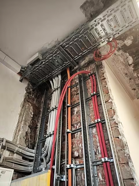 Offene Kabel in einer Wand im Klassenraum.