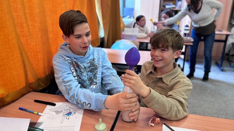 Die Kinder haben Spaß beim Experimentieren. Gerade haben sie selbst C02 hergestellt.