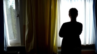 Frau als Schatten vor einem Fenster