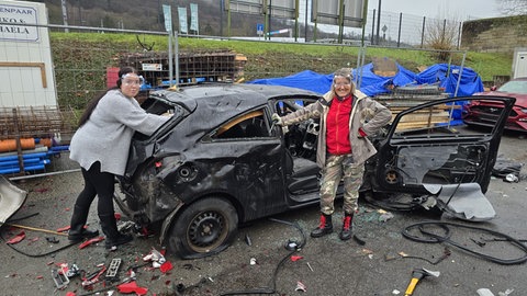 Alicja aus Trier und ihre Tochter haben viel Spaß dabei, ein Auto mit einer Axt und anderem Werkzeug zu zerlegen.