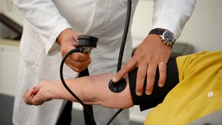 Ein Arzt hört einen Patienten ab. 