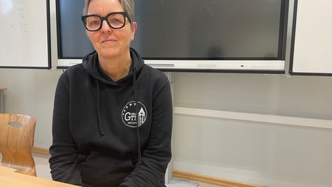 Eine Lehrerin sitzt vor einer Tafel. 