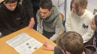 Mehrere Schüler beugen sich über eine Karte. 