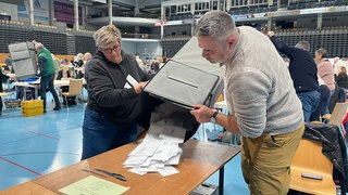 Helfer zählen Stimmen bei der Bundestagswahl 2025 in der Arena in Trier aus.