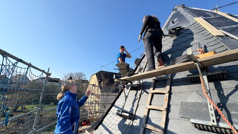 Vanessa Thieltges (links) bespricht sich mit einem weiteren Dachdeckermeister und der Auszubildenden.
