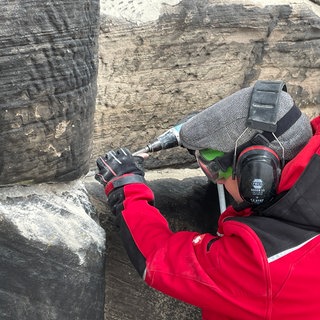 Steinmetzmeister Tobias Hartmann bei der Arbeit an der Porta Nigra. Mörtel aus den 1979er Jahren wird entfernt. 