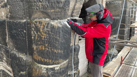 Steinmetzmeister Tobias Hartmann bei der Arbeit auf dem Gerüst an der Porta Nigra. 
