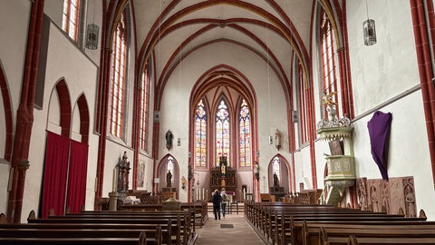 Ein belgisches Paar schaut sich in der Stiftskirche in Kyllburg die Renaissancefenster an.
