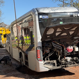 Nach einem Wasserrohrbruch in der Medardstraße in Trier hat sich ein Linienbus festgefahren. Ein Kran half bei der Bergung.