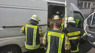 Feuerwehrleute befreiten einen Paketboten aus dem Inneren seines Transporters.