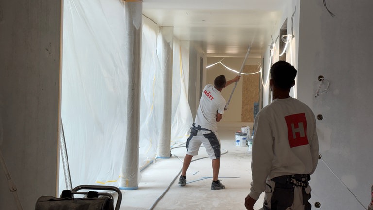 Ein Arbeiter besprüht die Decke des Kinderhospizes in Trier mit weißer Farbe.