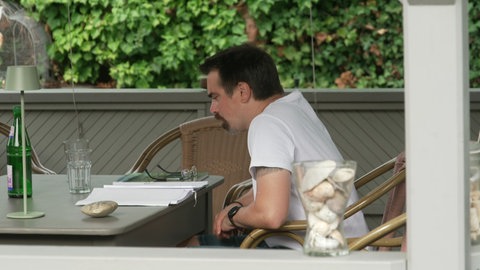 Peter Geltz sitzt in seinem Garten und schaut sein Notizbuch an. Er hat MECFS.
