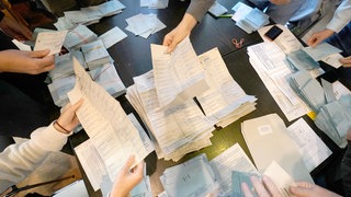 Stimmzettel bei einer Wahl werden von Wahlhelfern ausgezählt