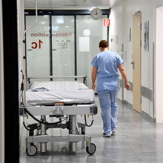 Ein Mitarbeiter im Gesundheitswesen geht auf einer Intensivstation den Flur entlang. 