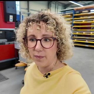 Eine Frau mit blonden Locken läuft durch eine Halle