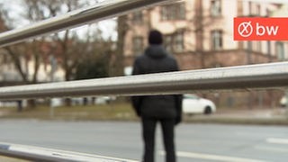 Ein Polizeibeamter steht an einer Straße, den Blick auf ein Amtsgericht und ein Gefängnis gerichtet.
