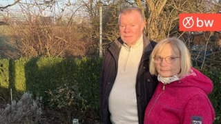 Jürgen und Elisabeth Wolf stehen in ihrem Garten und im Hintergrund sieht man das Gewerbegebiet von Weilimdorf, wo die neue LEA entstehen soll.