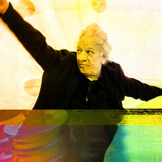 Der Autor, Komponist und Musiker FM Einheit breitet die Arme aus vor einem geschwungenen gelben Hintergrund, unter seinen Füßen sieht man links Maschinenteile, lila eingefärbt, und rechts bunte Farbverläufe.