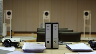 Tisch mit zwei Aktenordnern und drei Lausprechern im Hintergrund