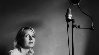 Antje Vowinckel sitzend neben einem Mikrofon