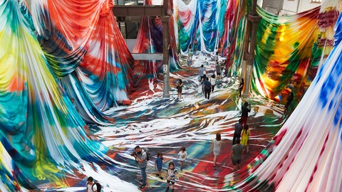 Besucher durch eine Installation mit bunten Stoffen.