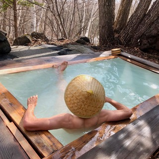 Mann mit japanischem Hut badet in einem Onsen, Japan