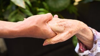 Symbolbild: Nahaufnahme einer jüngeren Hand, die eine ältere Hand hält
