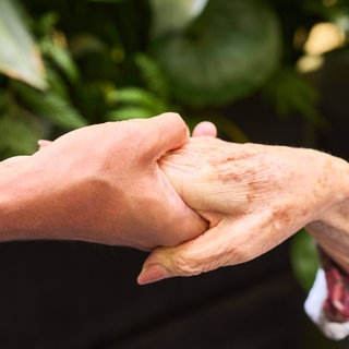 Symbolbild: Nahaufnahme einer jüngeren Hand, die eine ältere Hand hält
