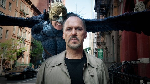 Szenenbild aus "Birdman" mit Michael Keaton im Vordergrund. Direkt hinter ihm fliegt Birdman und flüstert ihm ins Ohr