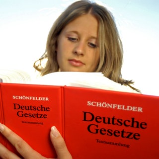 Junge Frau mit dickem Gesetzbuch: Der Großteil der Jurastudierenden sind Akademikerkinder, den Abschluss schafft man nur mit kostspieligen Repetitorien, der psychische Druck auf angehende Juristen ist enorm