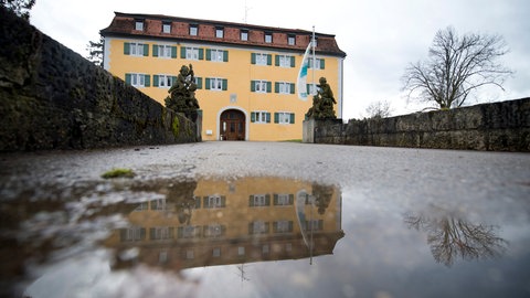 Das gelbe Gebäude spiegelt sich in einer Pfütze: Schloss Grafeneck wurde von den Nationalsozialisten im Oktober 1939 beschlagnahmt. 1940 wurden in Grafeneck mehr als 10.600 Menschen systematisch in einer Gaskammer ermordet. Die Opfer kamen aus Krankenanstalten und Heimen in Baden-Württemberg, Bayern, Hessen und Nordrhein-Westfalen. Heute erinnern eine Gedenkstätte und ein Dokumentationszentrum an die Geschichte.