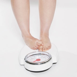Eine Person steht verlegen auf einer Waage