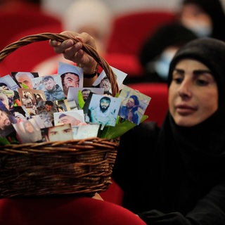 Eine schiitische Frau hält einen Korb voller Porträts von Hisbollah-Kämpfern, die während einer Kundgebung zum Märtyrertag der Hisbollah im südlichen Vorort von Beirut im Libanon im Kampf mit ihrer Gruppe starben