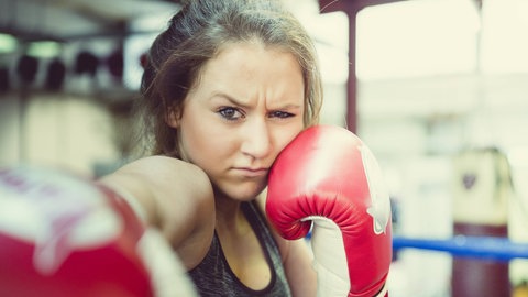 Ein Mädchen boxt mit grimmigem Gesichtsausdruck: Es gibt zahlreiche Beispiele für sexualisierte Gewalt im Sport. Betroffene fühlen sich gedemütigt oder erniedrigt. Fachleute erforschen das Ausmaß der sexualisierten Gewalt im Sport und welche Faktoren sie begünstigen. 