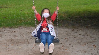 Ein Mädchen mit Gesichtsmaske schaukelt: Gibt es eine "Generation Corona"?