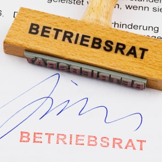 Stempel und Unterschrift "Betriebsrat" auf einem Schriftstück. Betriebsräte haben in Deutschland eine lange Tradition. Im Gesetz verankert, sollen sie die demokratische Kultur am Arbeitsplatz fördern und darauf achten, dass die Rechte der Beschäftigten geschützt werden. Werden sie heute noch gebraucht?