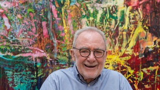 Gerhard Richter 2017 lächelnd vor seinem Gemälde "Abstract painting '946-3" (2016)