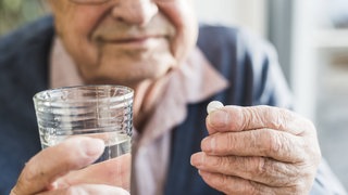 Ein Senior nimmt eine Tablette