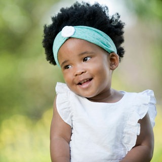 Schüchternes kleines Mädchen lächelt verlegen: Schüchterne Kinder können sich oft besser in andere hineinversetzen. Ein Defizit ist dieser Charakterzug nicht. Aber in der Schule haben sie es schwerer. Was hilft, sich zu trauen?