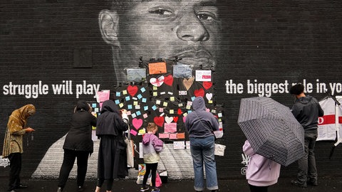 Menschen platzieren Unterstützungsbotschaften über dem beleidigenden Schriftzug auf dem Wandbild von Manchester-United-Stürmer und England-Spieler Marcus Rashford. Das Wandbild wurde am Morgen nach der Niederlage der englischen Fußballmannschaft zerstört. Mit Empörung haben Politik, Fußballverband und Gesellschaft in Großbritannien auf rassistische Beleidigungen gegen die englischen Elfmeter-Fehlschützen im EM-Finale im Juli 2021 reagiert.