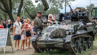 Offener Stützpunkt Hohe Düne in Warnemünde: Eine Familie schaut sich einen Panzer an, ein Bundeswehrsoldat erklärt: Bundesverteidigungsminister Boris Pistorius wünscht sich einen Mentalitätswechsel bei den Deutschen. Sie sollen "kriegstüchtig" werden. Und tatsächlich: Angesichts des russischen Kriegs floriert die Rüstungsindustrie, die Bundeswehr erfährt eine neue Wertschätzung.